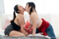 Girls kneeling on bed kissing on bed hair in ponytail